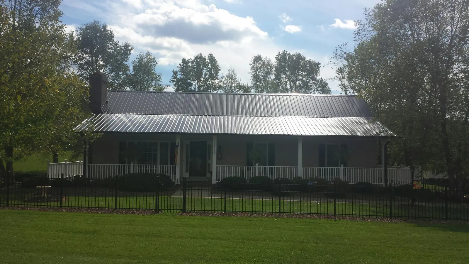 Gray metal roof on a brick ranch with a full width front porch — Gutter Guard Installation work by our crew in Greensboro